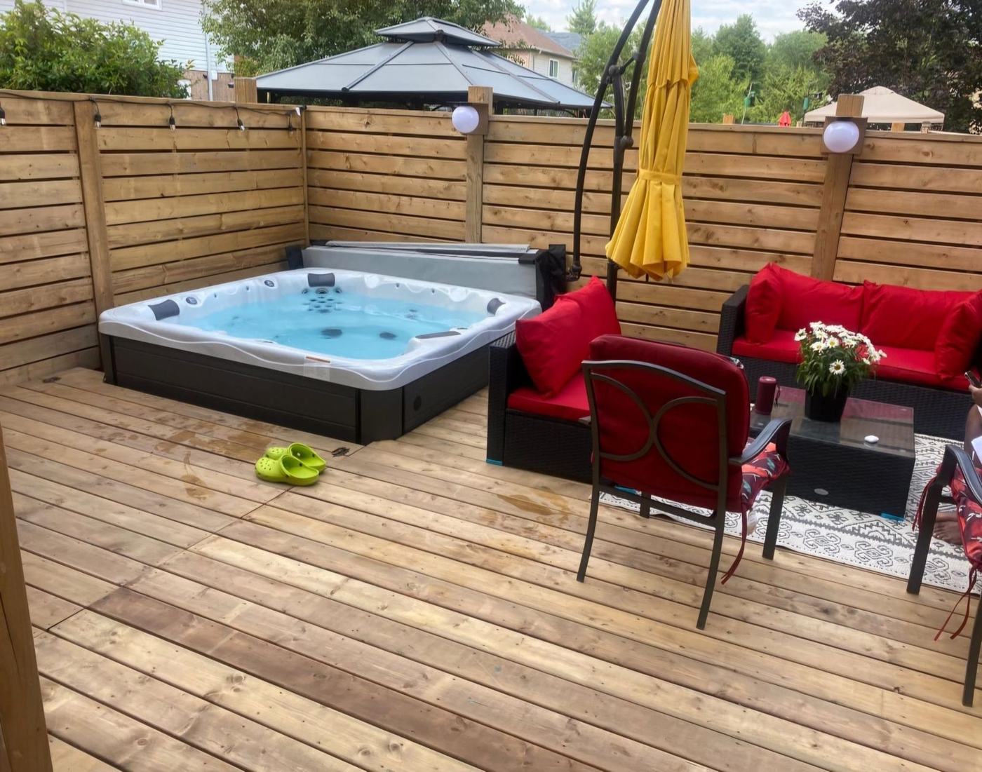 Wood deck with a hot tub, seating and a horizontal privacy screen