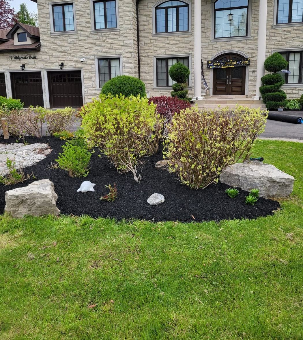 Front beds with boulders, shrubs and fresh black mulch at a stone estate home