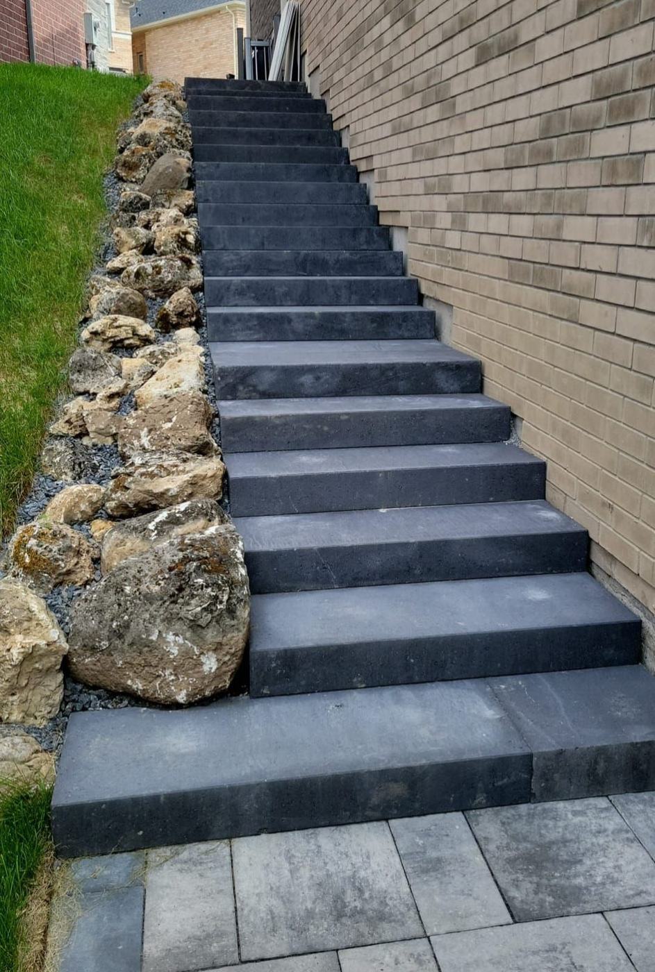 Long flight of stone steps down a side yard, retained with armour rock